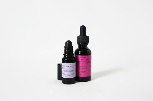 Two black dropper bottles with pink labels on a white background