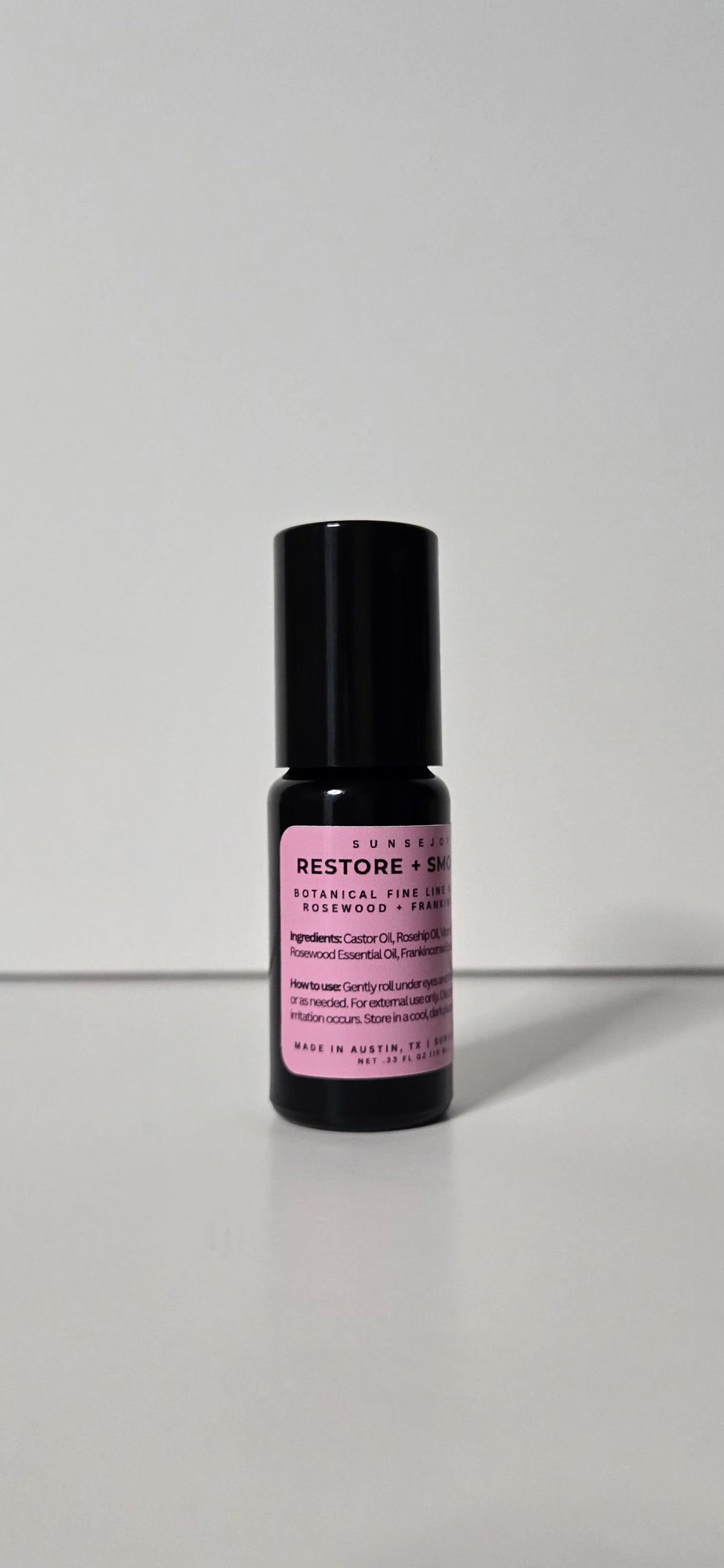 Skincare serum bottle with black cap and purple label on a white background