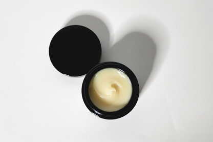 Black container with body butter in it on a white background