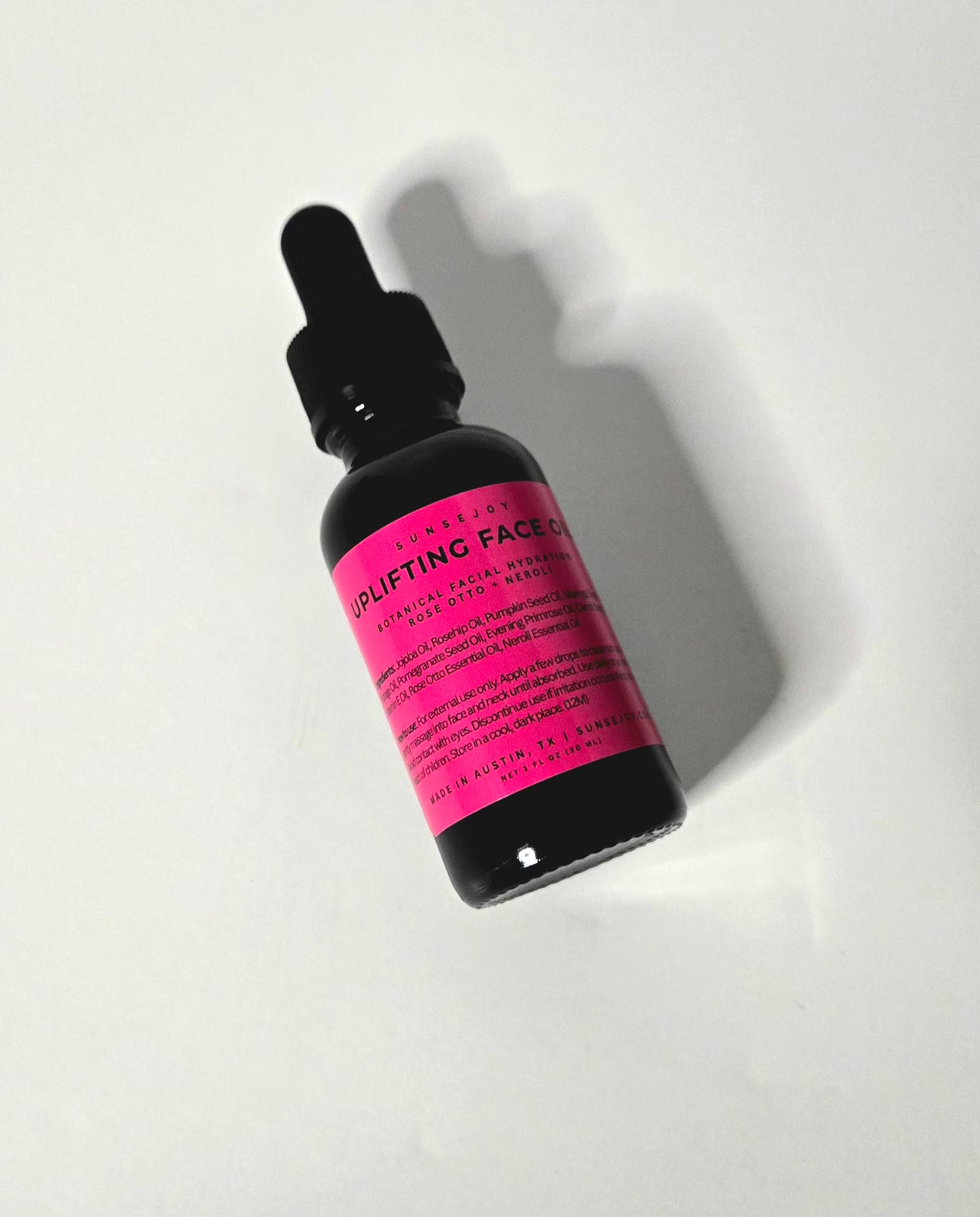 Skincare dropper bottle with pink label on a white background