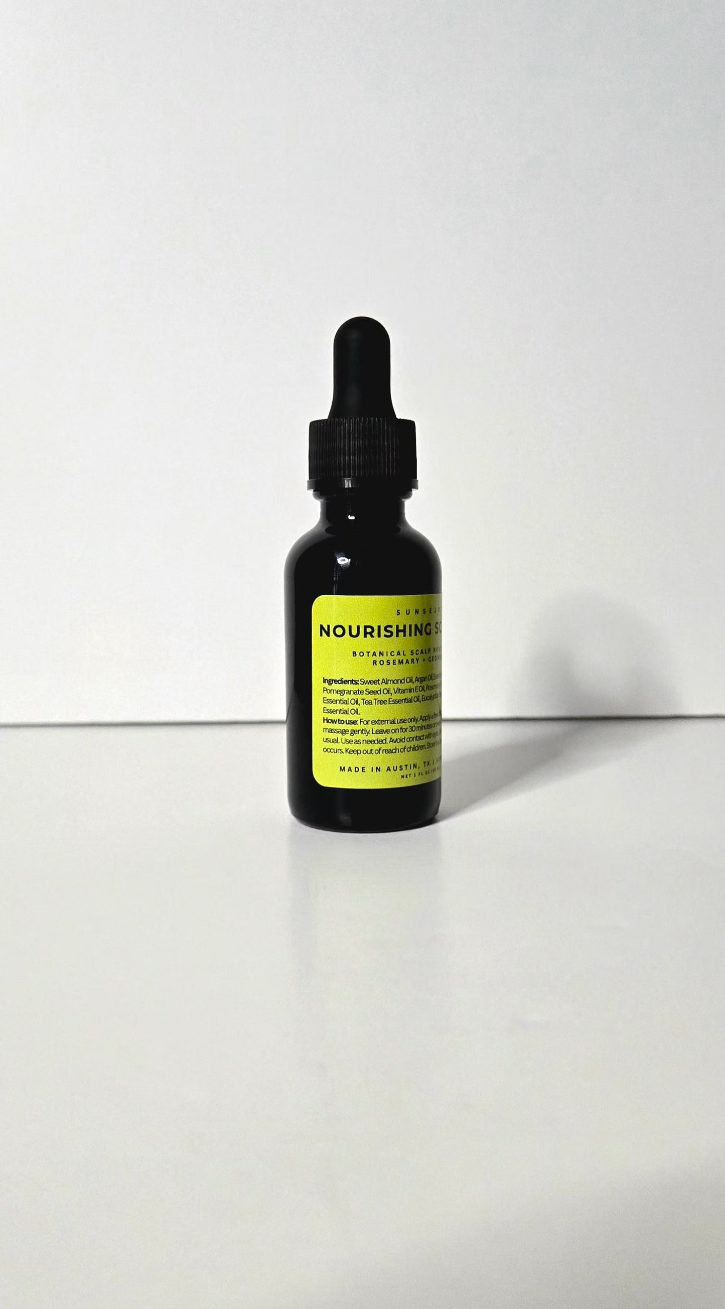 Black dropper bottle with a yellow label on a white background