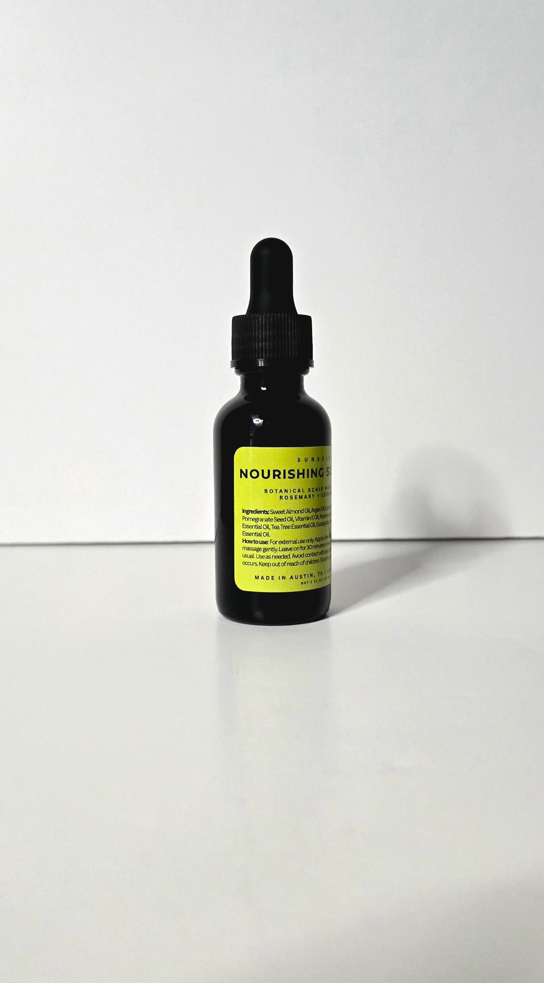 Black dropper bottle with a yellow label on a white background