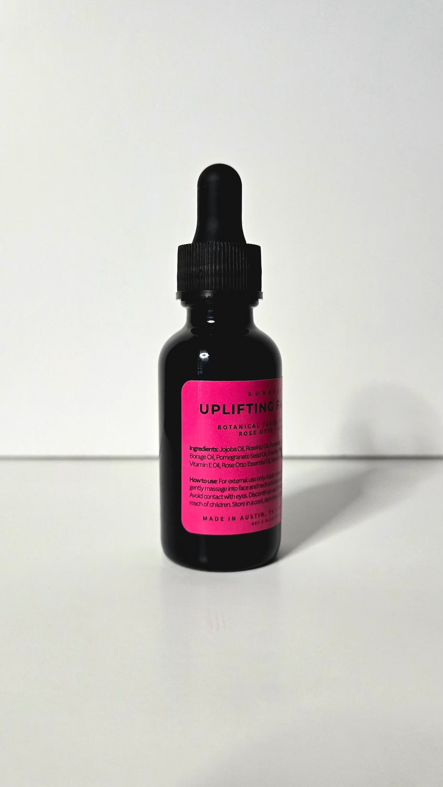 Black dropper bottle with pink label on a white background