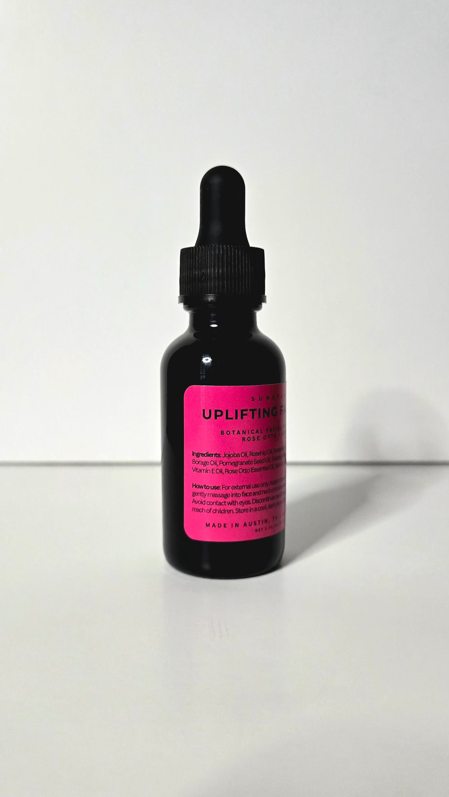 Black dropper bottle with pink label on a white background