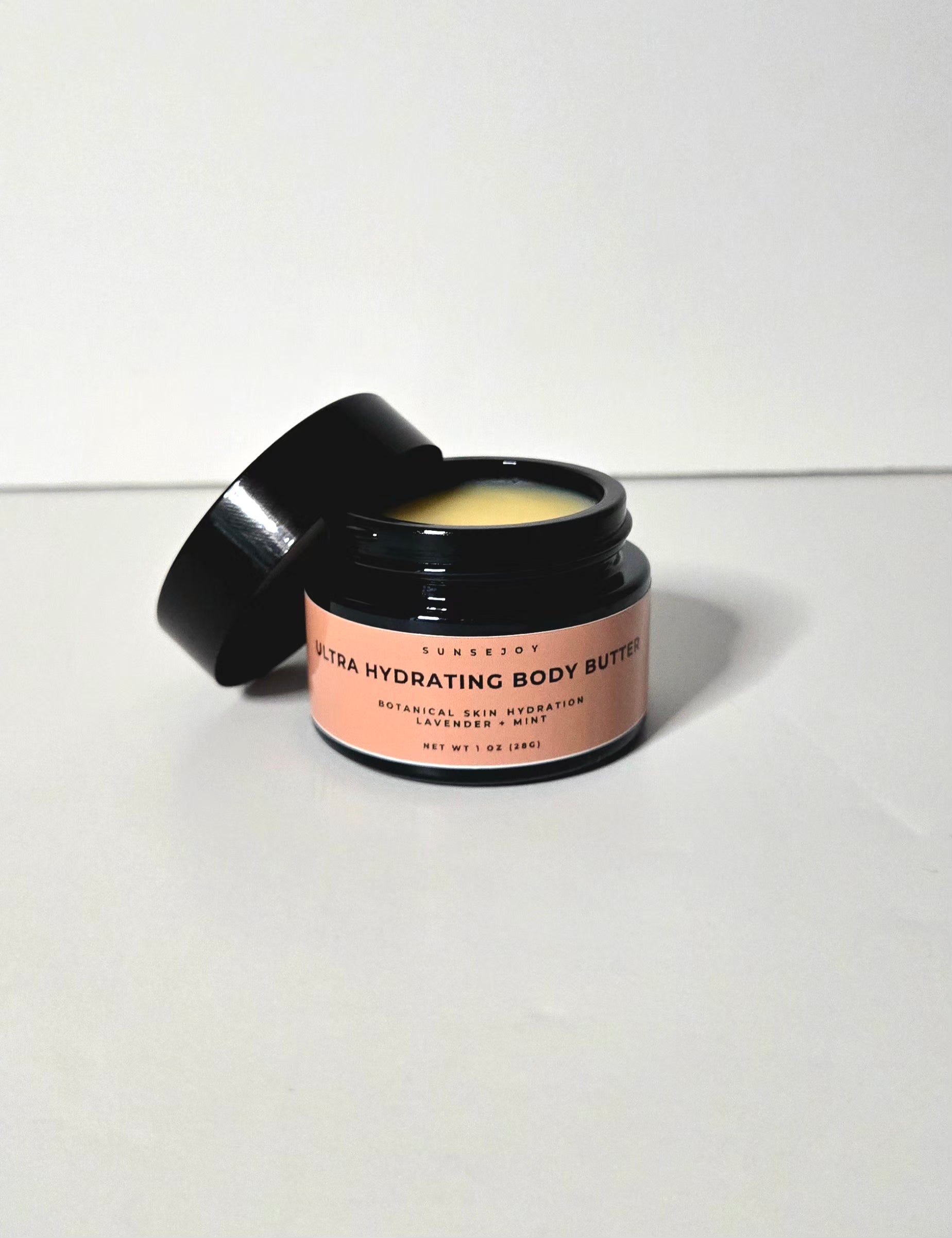 Jar of ultra hydrating body butter with a pink label on a white background